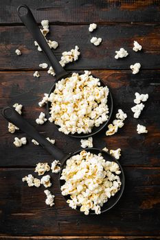 Heap of salted popcorn, on old dark wooden table background, top view flat lay