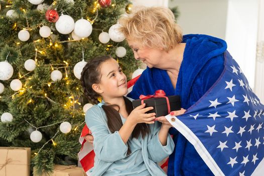 Family holding flag of USA at christmas. grandmother and granddaughter.