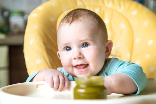 Little baby is eating broccoli vegetable puree. Selective focus. people.