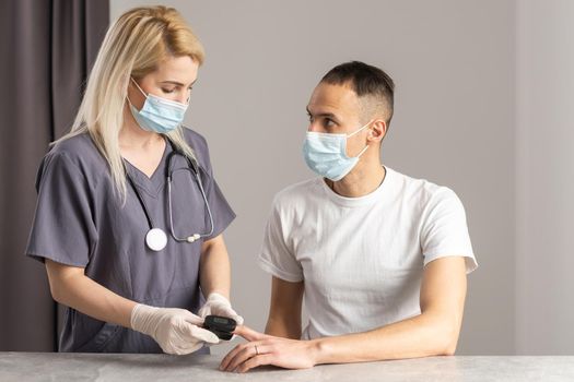 Close-up image of doctor measuring oxygen saturation of patient with pulse oximeter device