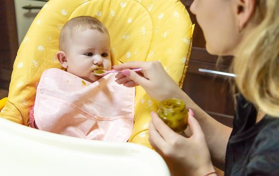 Mom feeds baby with vegetable puree. Selective focus. Food.