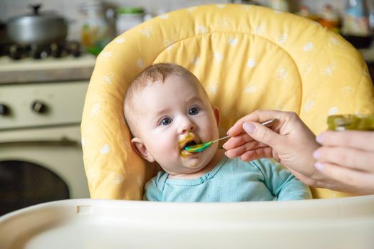 Little baby is eating broccoli vegetable puree. Selective focus. people.