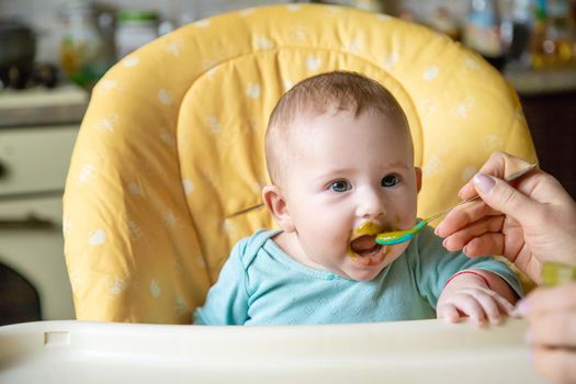 Little baby is eating broccoli vegetable puree. Selective focus. people.