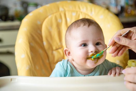 Little baby is eating broccoli vegetable puree. Selective focus. people.