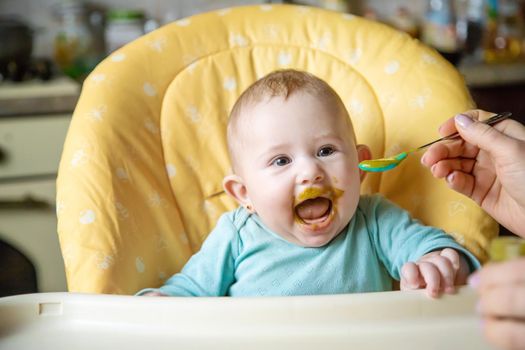 Little baby is eating broccoli vegetable puree. Selective focus. people.