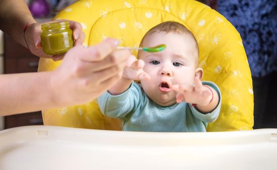 Little baby is eating broccoli vegetable puree. Selective focus. people.