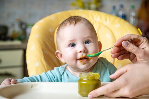 Little baby is eating broccoli vegetable puree. Selective focus. people.