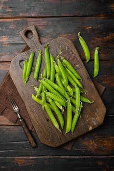 Fresh picked green pea, on old dark wooden table background, top view flat lay