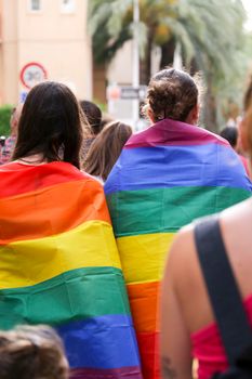 Santa Pola, Alicante, Spain- July 2, 2022: Spanish People attending Gay Pride Parade with rainbow flags, banners and colorful costumes