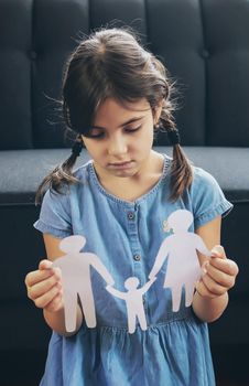 Child with a paper family in his hands. the concept of divorce, custody and child abuse. Selective focus. People.