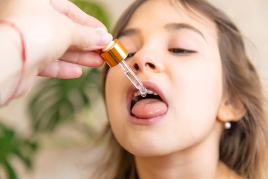 mother giving vitamin drops with dropper to her child. dietary supplements for kids. Selective focus.