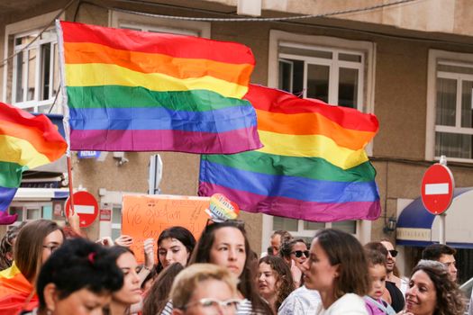 Santa Pola, Alicante, Spain- July 2, 2022: Spanish People attending Gay Pride Parade with rainbow flags, banners and colorful costumes