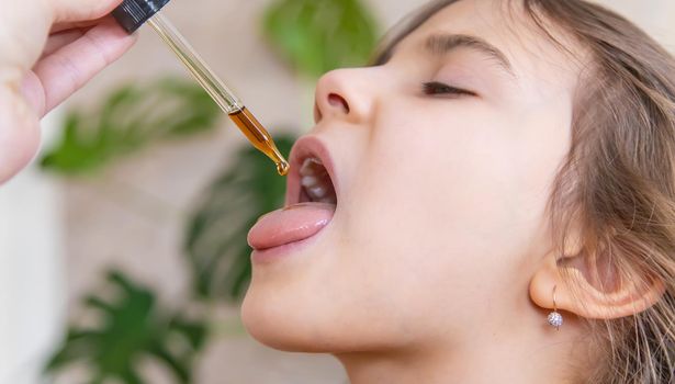 mother giving vitamin drops with dropper to her child. dietary supplements for kids. Selective focus.