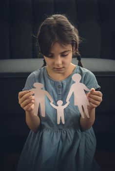 Child with a paper family in his hands. the concept of divorce, custody and child abuse. Selective focus. People.