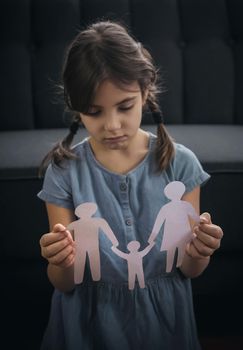 Child with a paper family in his hands. the concept of divorce, custody and child abuse. Selective focus. People.