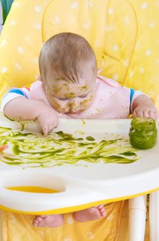 Little baby eats broccoli puree himself. Selective focus. People.