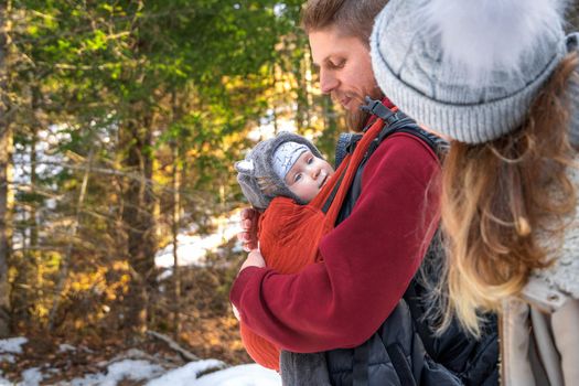Babywearing winter walk of young parents with their children outdoor, copy space.