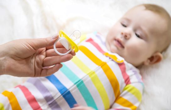 The mother gives the baby a pacifier. Selective focus. Child.