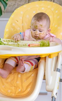 Little baby eats broccoli puree himself. Selective focus. People.