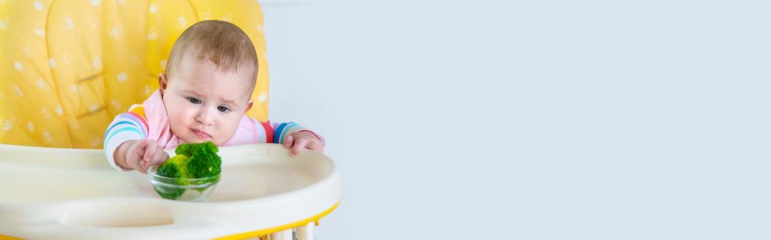 Little baby is eating broccoli vegetable puree. Selective focus. People.