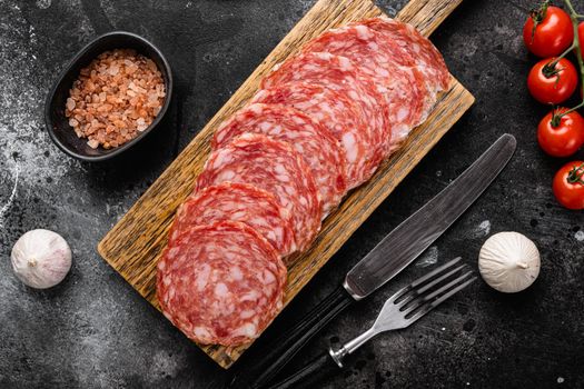 Thinly Sliced Milano salami set, on black dark stone table background, top view flat lay