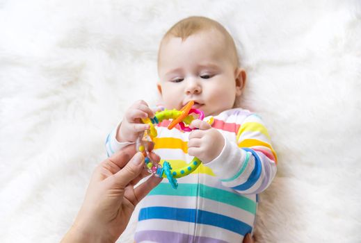 The mother gives a rattle to the baby. Selective focus. child.