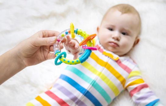 The mother gives a rattle to the baby. Selective focus. child.