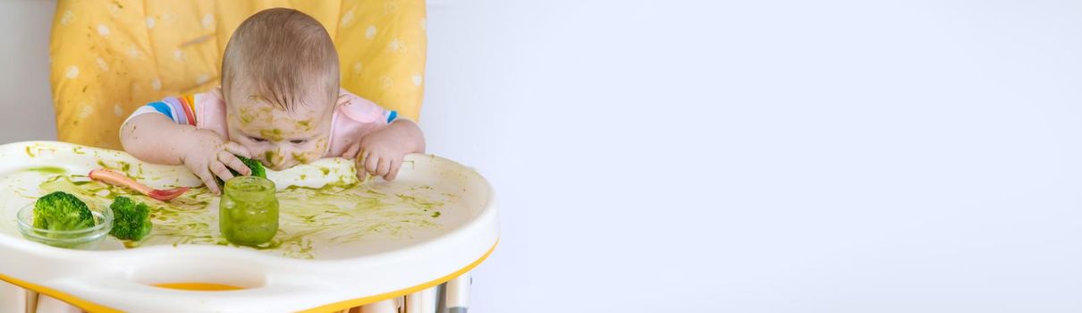 Little baby eats broccoli puree himself. Selective focus. People.