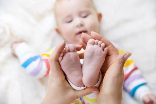 The mother holds the legs of her baby. Selective focus. Child.