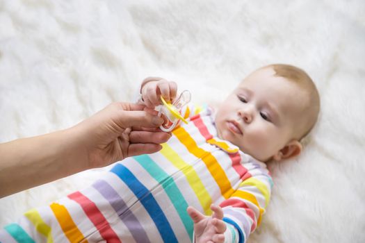 The mother gives the baby a pacifier. Selective focus. Child.