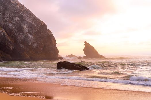 Sunset on the Ocean wild beach stormy weather. Praia da Adraga sandy beach with picturesque landscape background, Sintra Cascais Portugal Vitality of blue energy and clear ocean water