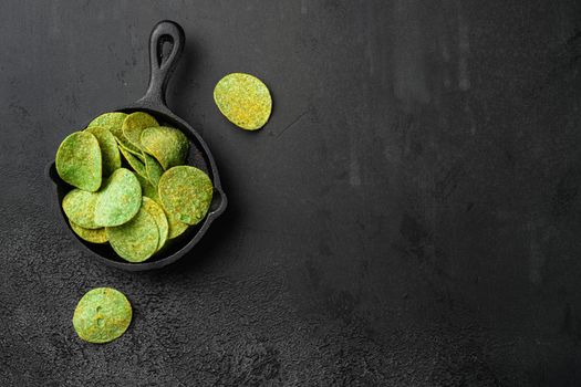 Green Cheddar Jalapeno crispy bite Potato Chips, on black dark stone table background, top view flat lay, with copy space for text