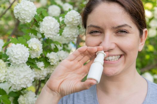 Caucasian woman uses a nasal spray while walking in the park