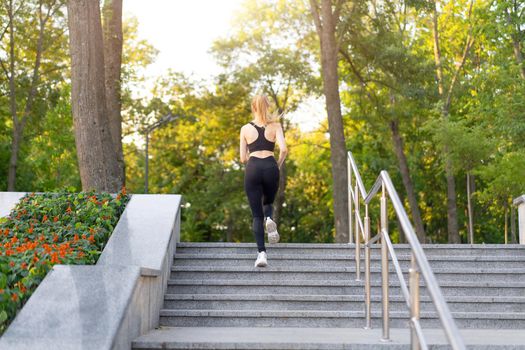 Sport and Fitness. Fit Woman Running up stairs Summer Sunny Morning Caucasian Athletic Female Jogging Outdoor Cardio Training Active Healthy Lifestyle Dressed Black Sportswear Motivation Concept
