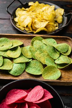 Green potato chips, on old dark wooden table background