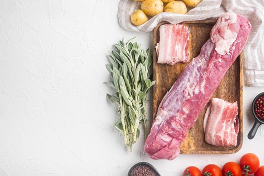 Raw pork tenderloin with ingredients and herbs set, on wooden tray, on white stone background, top view flat lay , with copyspace and space for text