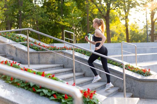 Sport and Fitness. Fit Woman Running up stairs Summer Sunny Morning Caucasian Athletic Female Jogging Outdoor Cardio Training Active Healthy Lifestyle Dressed Black Sportswear Motivation Concept