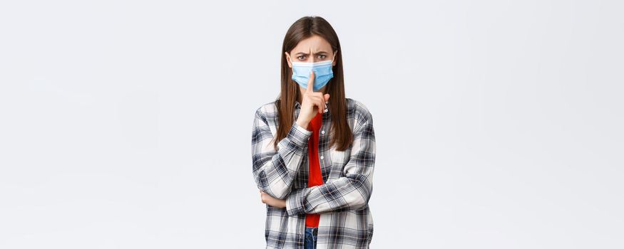 Coronavirus outbreak, leisure on quarantine, social distancing and emotions concept. Serious-looking girl in medical mask, shushing with irritated face, frowning tell be quiet or keep silence.