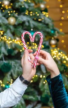 Christmas lollipops in the hands of a man and a woman. Selective focus. Holiday.