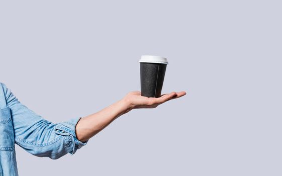 Hand holding a coffee to go on isolated background, Close up of hand holding a paper cup of coffee.  Arm holding glass of coffee isolated