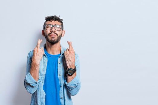 Worried person crossing his fingers making a wish, concerned man apologizing, hopeful man asking for help or apologizing, superstitious man crossing his fingers asking for something