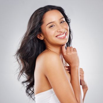 Cropped portrait of an attractive young woman posing in studio against a grey background.