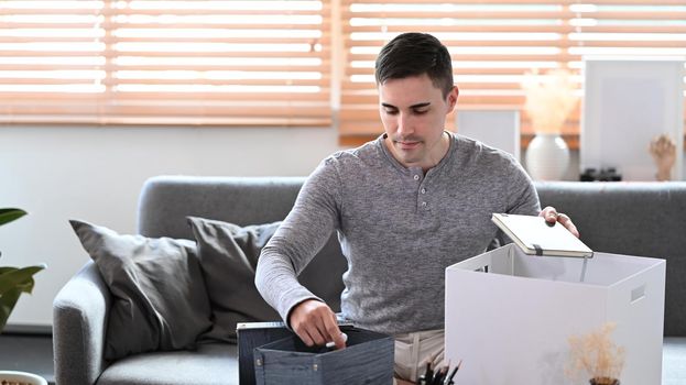 Young man preparing personal stuff for moving into new house.