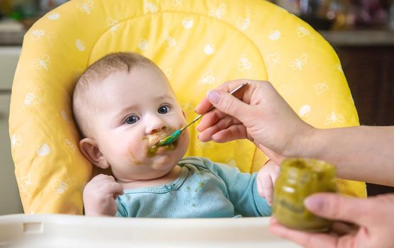 Little baby is eating broccoli vegetable puree. Selective focus. people.