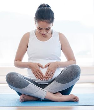 Shot of a pregnant woman doing yoga at home.