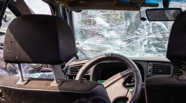 Damaged car window after an accident. Broken windshield as a result of an accident, inside view. Cabin interior details, view from the cab. Safe movement. Broken windshield. Glass crack and damage