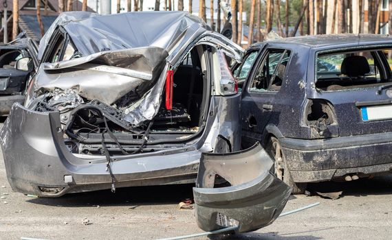 Broken car after a traffic accident in the parking lot of a repair station. Car body damage workshop outdoors. Sale of insurance cars. Accident on the street, car after a collision in the city