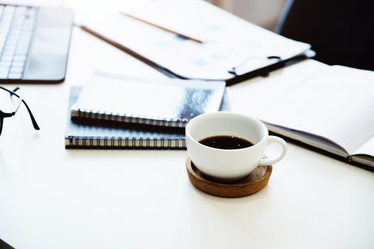 Focus on coffee mugs with books, documents with tablet computers on the desk.