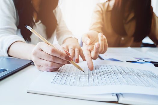 Negotiation, Analysis, Discussion, Asian woman economist and marketer pointing to a financial data sheet to plan investments to prevent risks and losses for the company.