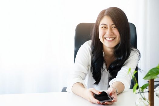 Portrait of a young Asian woman smiling happily while taking a break after work.